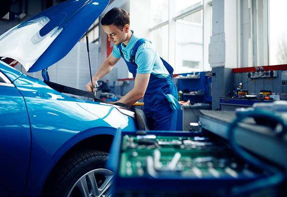 Auszubildender repariert ein Fahrzeug in der Werkstatt