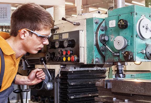 Ein Auszubildender in der Metallbranche arbeitet an einer Fräsmaschine