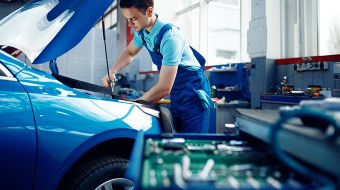 Auszubildender repariert ein Fahrzeug in der Werkstatt