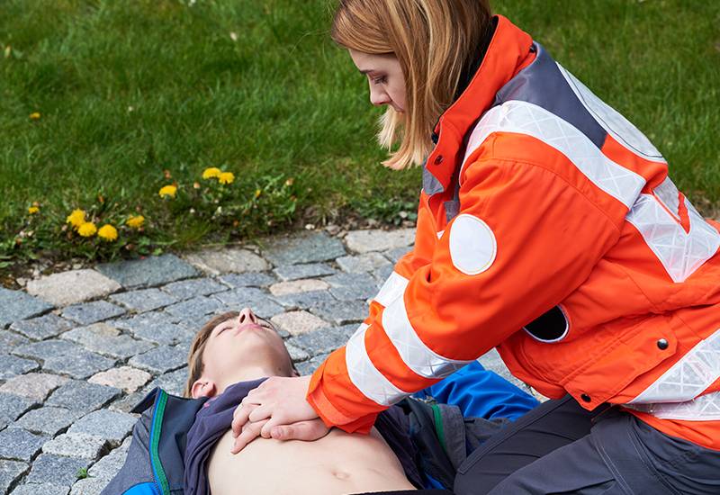 Junge Sanitäterin leistet erste Hilfe bei einem bewusstlosen jungen Mann